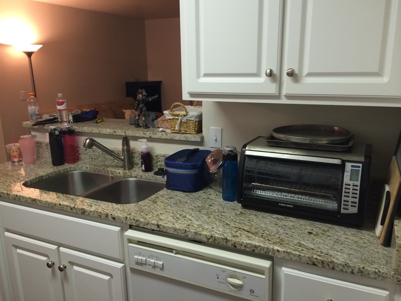 Across from stove, to the left of the pantry